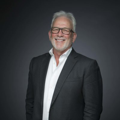 A man wearing an eyeglass with black frame, white polo, and black suit